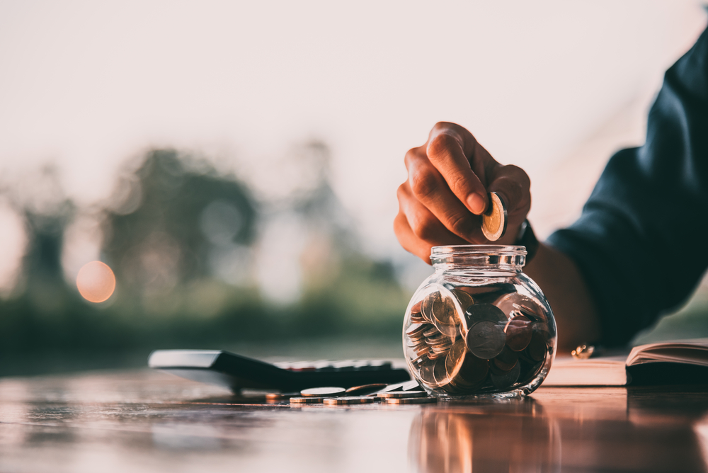 Person putting coins in a coin jar