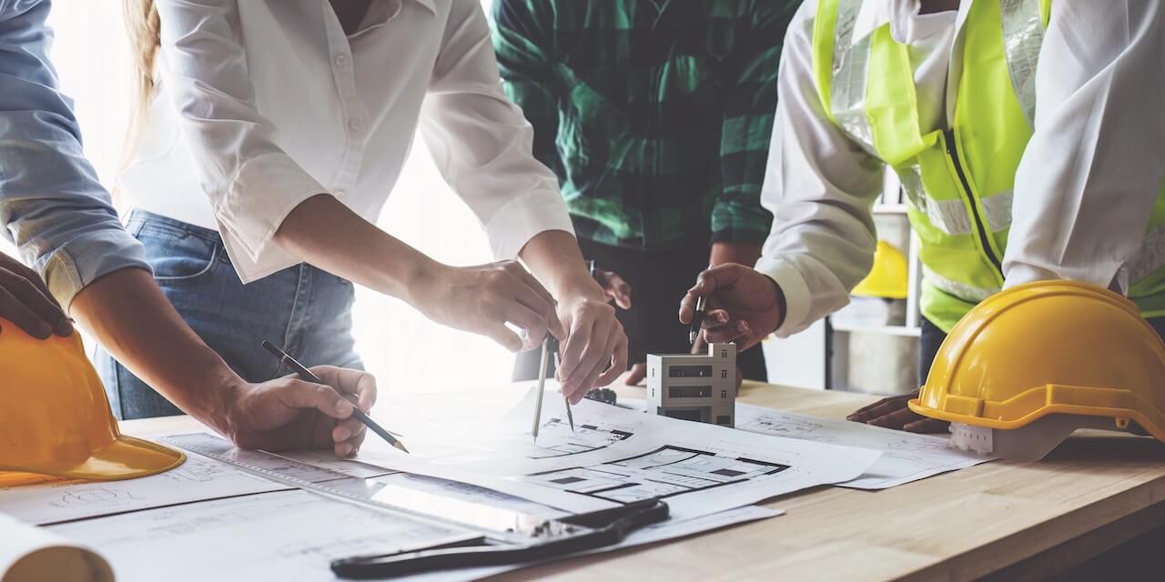 Construction professionals reviewing large-format blueprints at an active job site