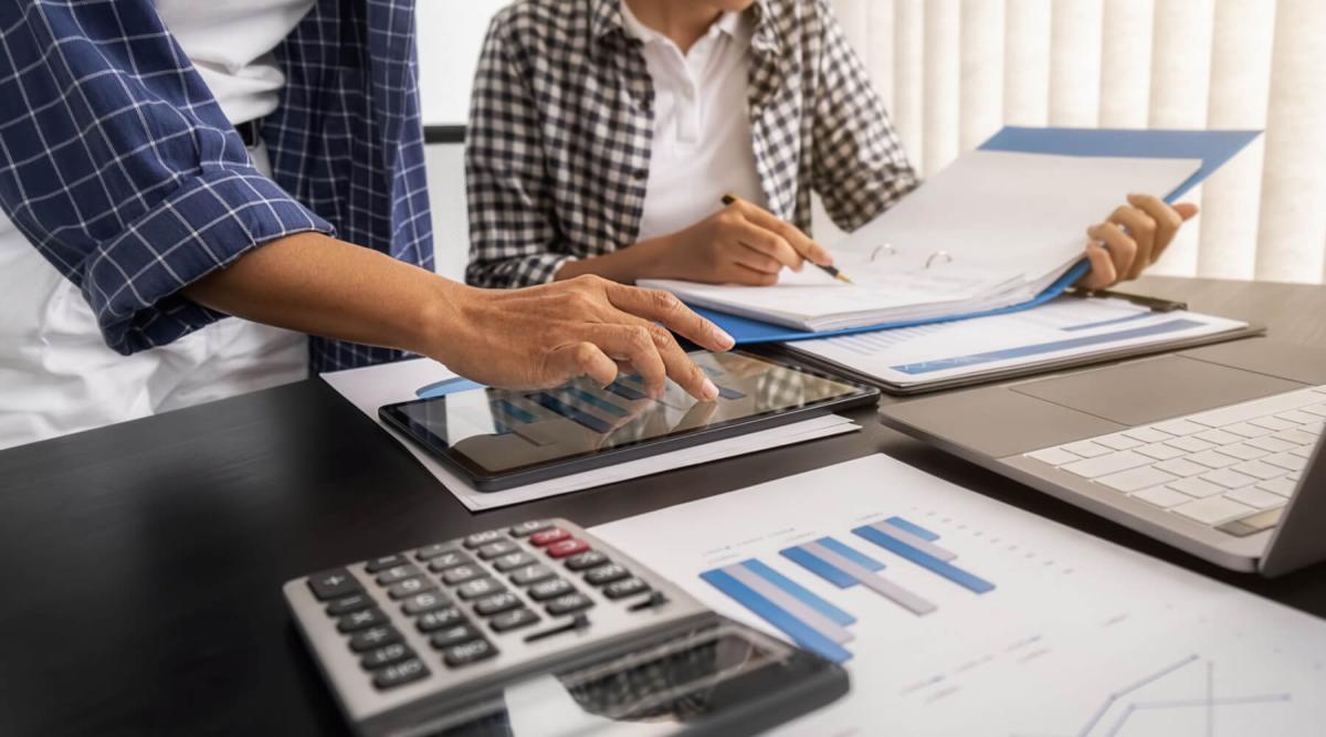 two accountants collaborating on screens and paper