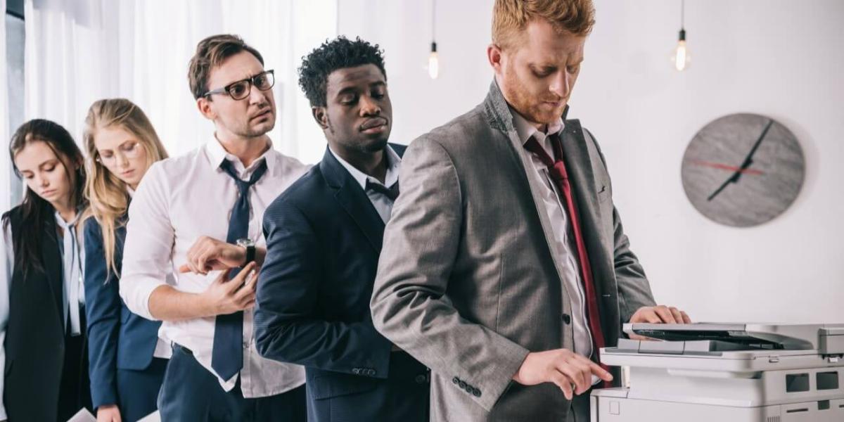 multiple coworkers crowded around one copier waiting their turn